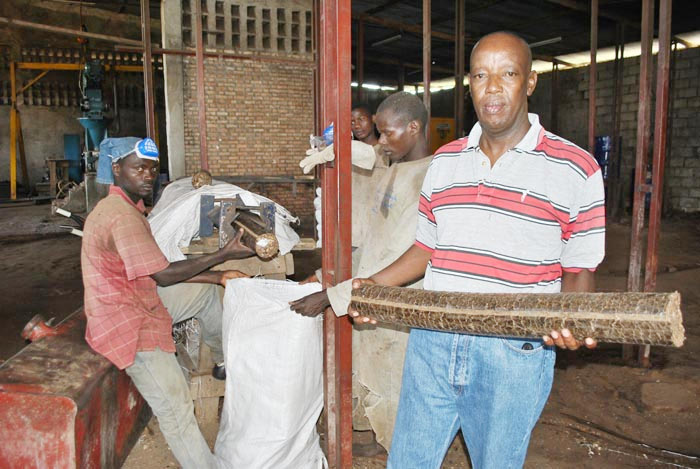 Ephraïm Ndayishima devant un concasseur. A sa gauche, des sacs contenant des briquettes à vendre ©Iwacu