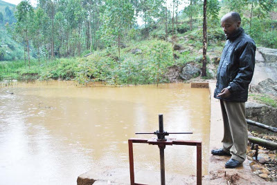 Léonidas Ndikuryayo, membre de l’association pour le développement du centre de Rutabo, nous fait découvrir le lac de retenue de la micro-centrale hydroélectrique ©Iwacu