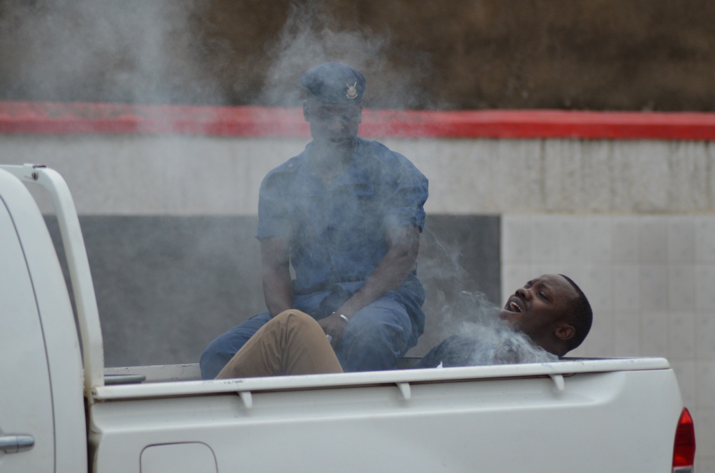 A young man handcuffed in a tear gas smosky car