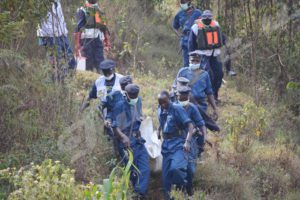 Police officers carrying one of the bodies to the main road.