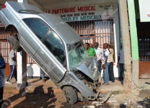 A car’s rear-wheels get caught on high of a pillar of a roadside building it has ploughed into.