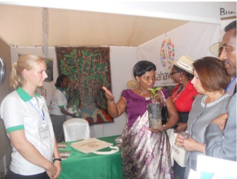 Odette KAYITSI (plant de caféier à la main), Ministre de l’Agriculture et de l’Elevage au stand de Kahawatu lors de la 11eme conférence et exposition du café africain. ©Iwacu