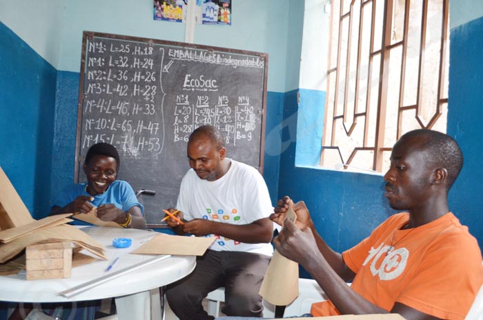 Hugues Nimpagaritse en t-shirt blanc, assemblant  les papiers kraft pour en faire un emballage